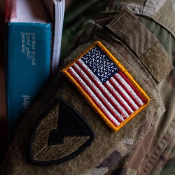 Close up showing American flag patch on uniform of a student veteran holding books.