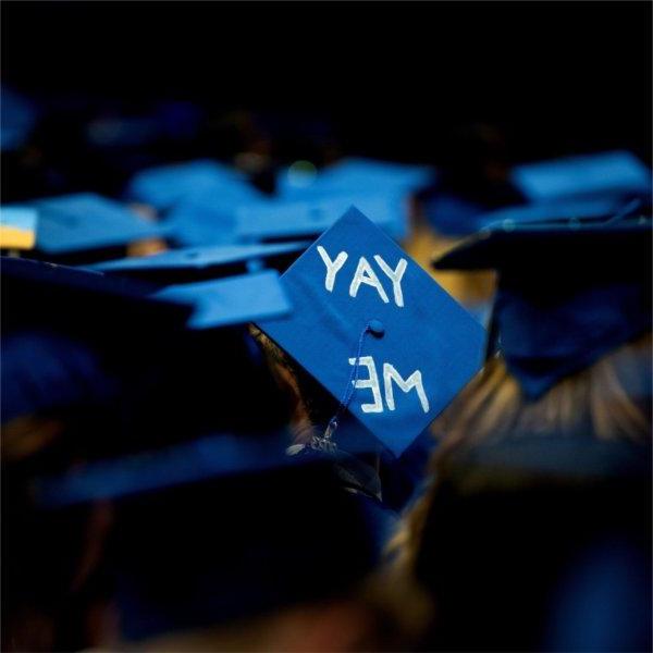 A person wears a graduation cap with the words, "Yay me."